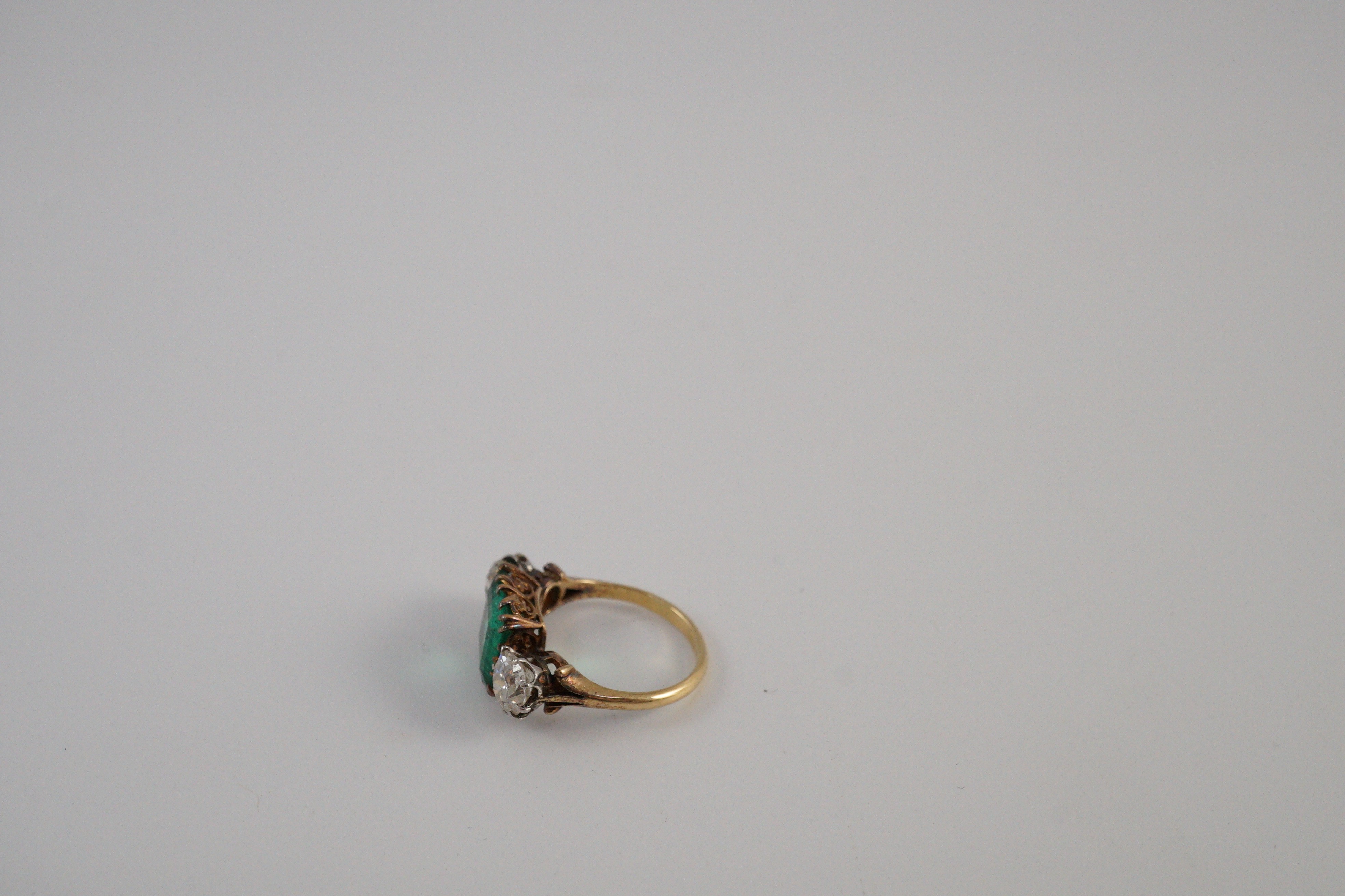 An early 20th century 18ct gold, square cut single stone emerald and two stone cushion cut diamond set dress ring